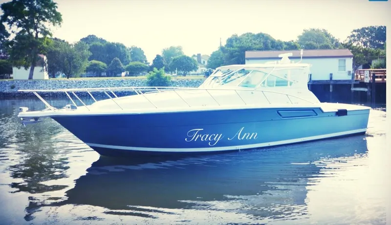 Slide: The Image of 1991 Tiara Yachts 4300 Open boat named "Tracy Ann" on calm water near shoreline. - 4