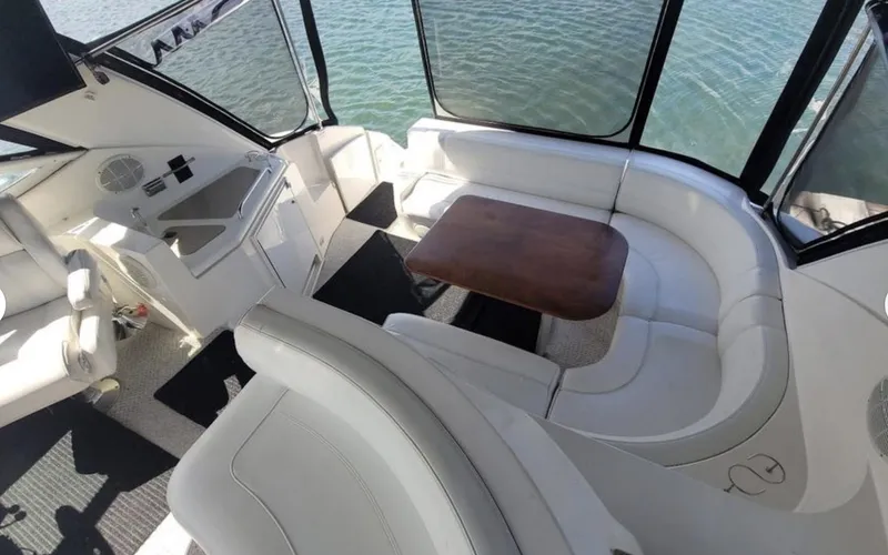 Slide: The Image of 2003 Cruisers Yachts 4370 Express interior with white seating and wooden table. - 5