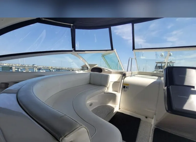 Slide: The Image of 2003 Cruisers Yachts 4370 Express interior with curved seating and marina view. - 7