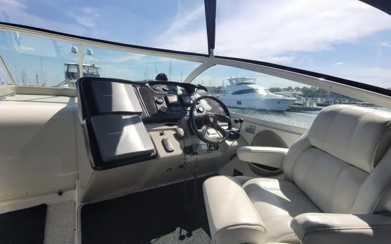 Slide: The Image of 2003 Cruisers Yachts 4370 Express helm with luxurious seating and marina view. - 8