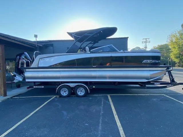 Slide: The Image of 2024 Avalon Catalina 2585 VRB pontoon boat on a trailer in a parking lot. - 0