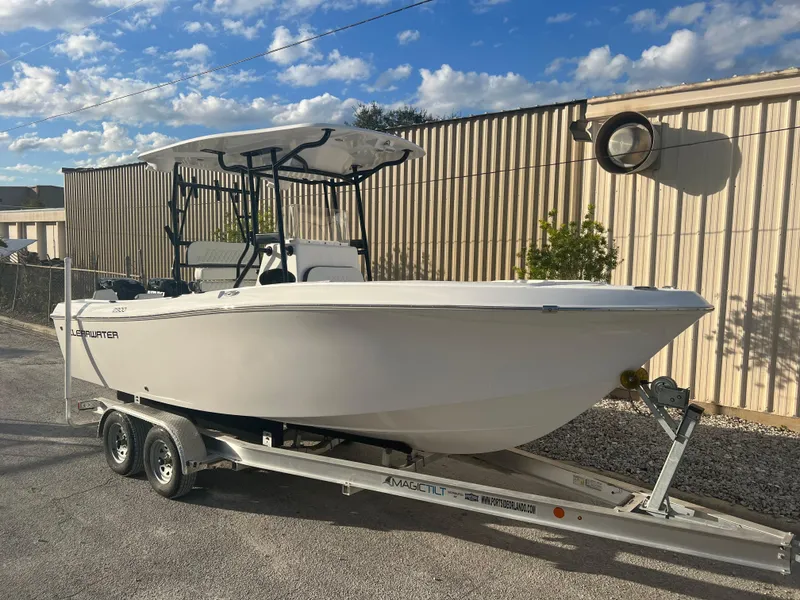 Slide: The Image of 2022 Clearwater 2300 boat on trailer, parked outdoors under a blue sky. - 2
