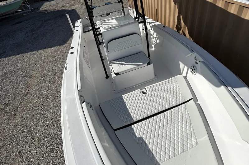 Slide: The Image of 2022 Clearwater 2300 boat interior with white cushioned seating and diamond-patterned flooring. - 25
