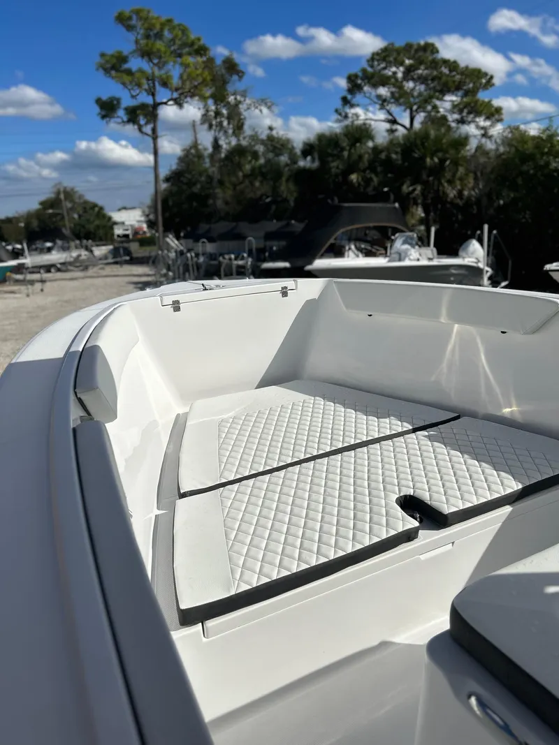 Slide: The Image of 2022 Clearwater 2300 boat with white cushioned seating, docked under a clear blue sky. - 7