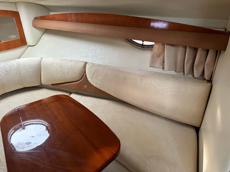 Slide: The Image of Interior of 2007 Four Winns 258 Vista boat with cushioned seating and wooden table. - 18