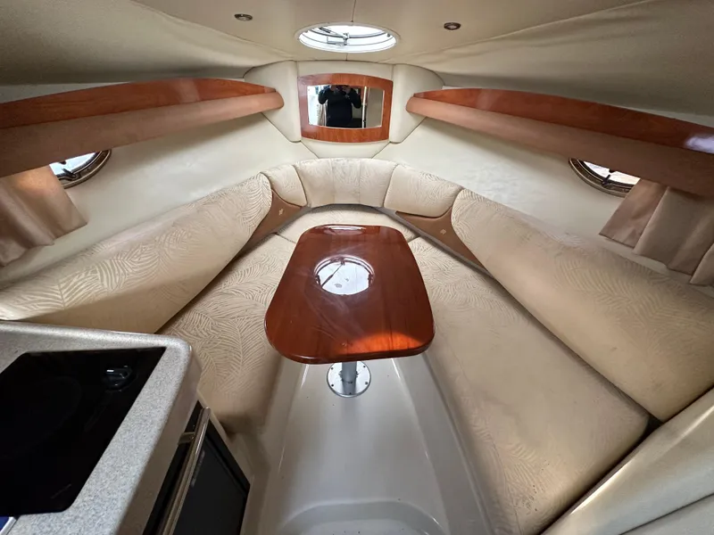 Slide: The Image of Interior cabin of a 2007 Four Winns 258 Vista boat with beige seating and wooden table. - 2