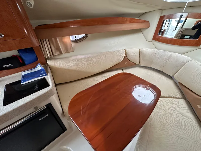 Slide: The Image of Interior of 2007 Four Winns 258 Vista boat with cushioned seating and wooden table. - 20