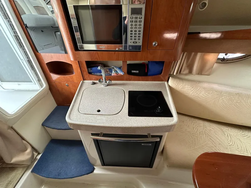 Slide: The Image of 2007 Four Winns 258 Vista boat interior kitchen with microwave, sink, and stove. - 21