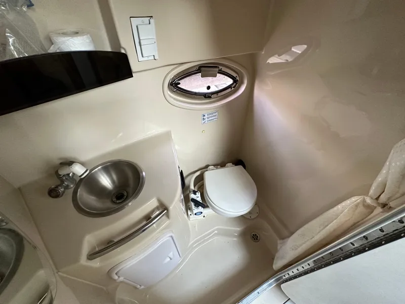 Slide: The Image of 2007 Four Winns 258 Vista boat bathroom with sink, toilet, and porthole window. - 23