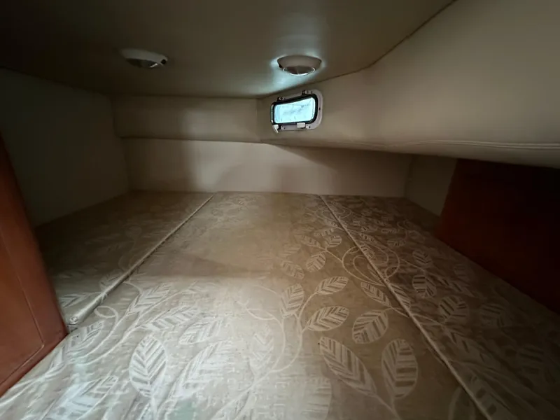 Slide: The Image of 2007 Four Winns 258 Vista cabin interior with patterned bedding and small window. - 26