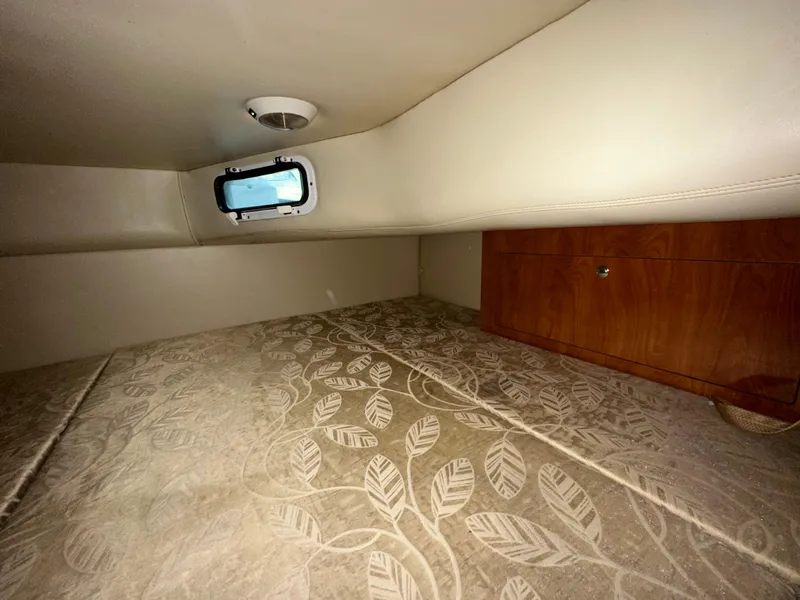 Slide: The Image of Interior cabin of 2007 Four Winns 258 Vista boat with patterned bedding and small window. - 27