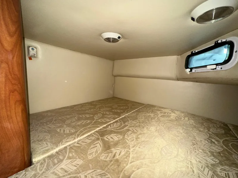 Slide: The Image of 2007 Four Winns 258 Vista cabin interior with patterned bedding and small window. - 28