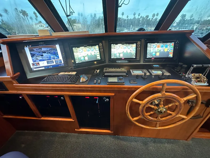 Slide: The Image of Control panel of a 2009 Little Hoquiam 68 Long Range Sportfisher with multiple screens and wooden steering wheel. - 43