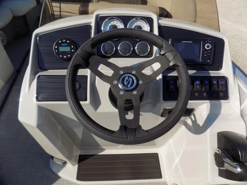 Slide: The Image of 2024 Sylvan Mirage 8522 CLZ boat dashboard with steering wheel and control panel. - 8