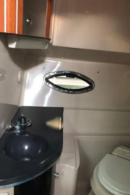 Slide: The Image of 2004 Doral Intrigue boat bathroom with sink, toilet, and porthole window. - 16