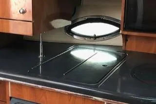 Slide: The Image of 2004 Doral Intrigue boat interior kitchen with wooden cabinets and a small window. - 7