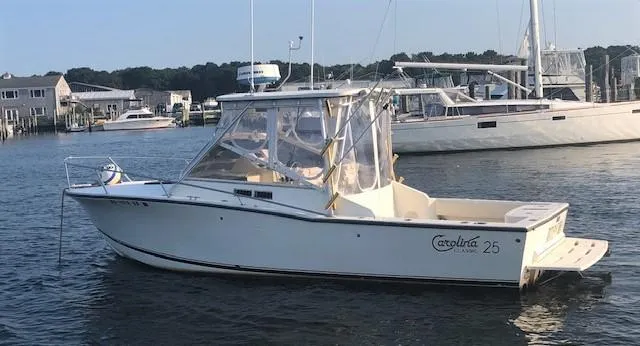 The Image of 2003 Carolina Classic 25 I/O boat docked in a marina, featuring a sleek design and enclosed cabin. - 0