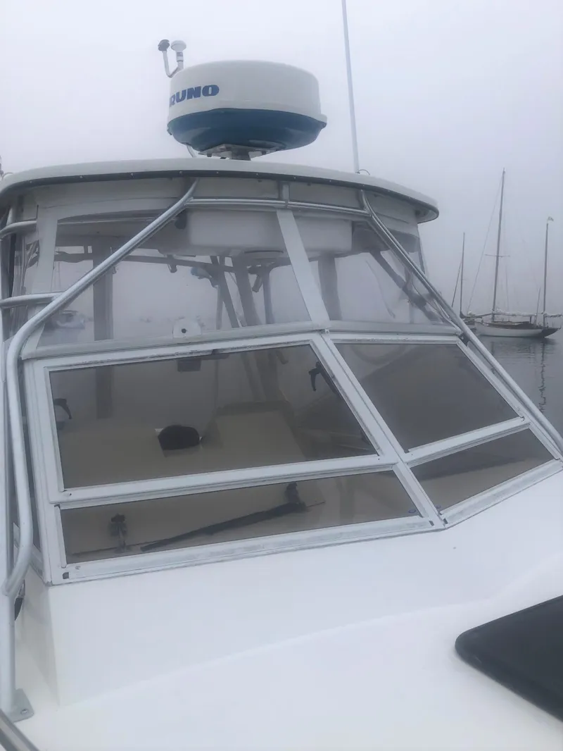 Slide: The Image of 2003 Carolina Classic 25 I/O boat with radar, docked in a foggy marina. - 11