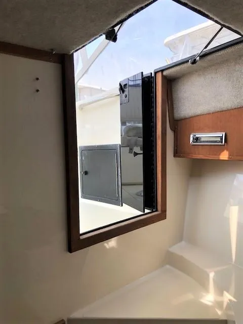 Slide: The Image of 2003 Carolina Classic 25 I/O cabin interior with window and storage compartment. - 30