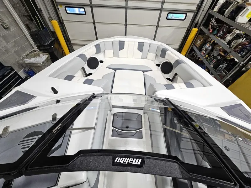 Slide: The Image of 2024 Malibu 21 LX-R boat interior with white and gray seating in a garage. - 11