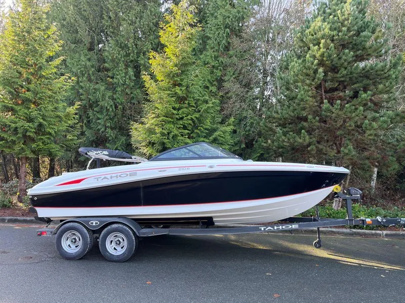 The Image of 2024 Tahoe 210 Si boat on trailer, parked near lush green trees. - 0