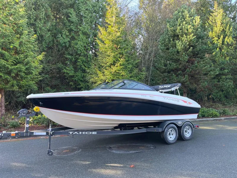 Slide: The Image of 2024 Tahoe 210 Si boat on trailer, parked outdoors near trees. - 1