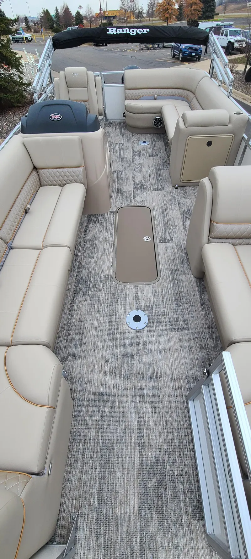 Slide: The Image of 2024 Ranger Reata 223C boat interior with beige seating and wood-style flooring. - 8