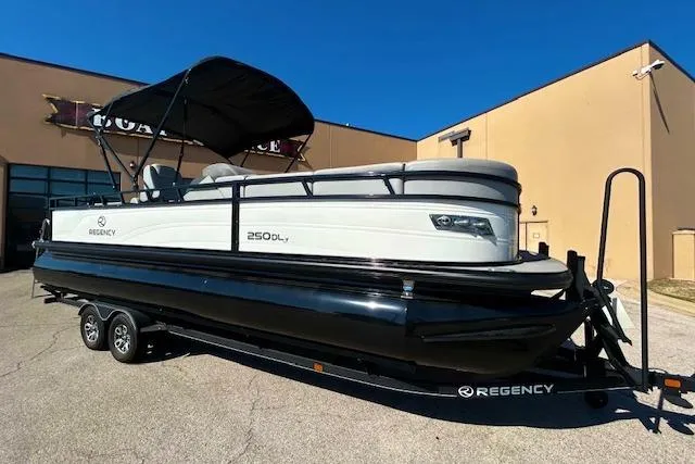 The Image of 2024 Regency 250 DL3 pontoon boat on trailer, parked outside service center. - 0