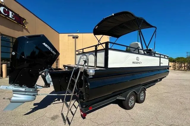 Slide: The Image of 2024 Regency 250 DL3 pontoon boat with canopy on trailer, parked outdoors. - 3