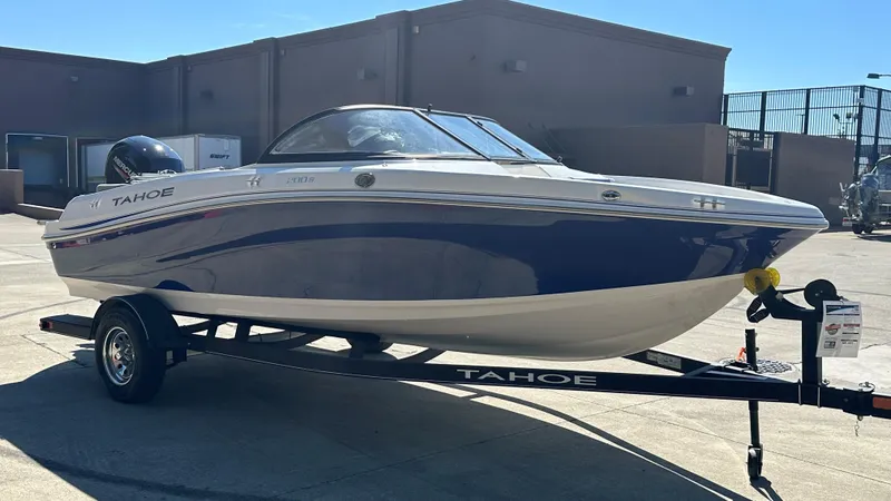 The Image of 2024 Tahoe 200 S boat on trailer, blue and white design, parked outdoors. - 0