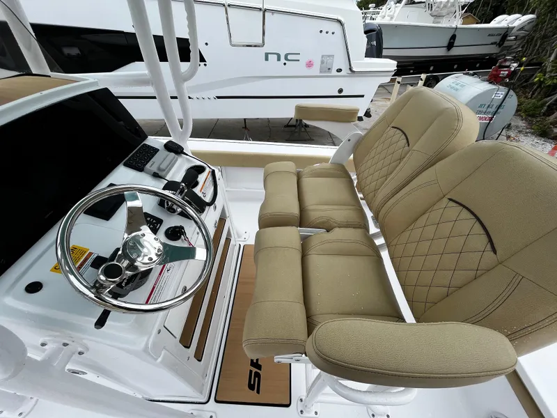 Slide: The Image of 2024 Sportsman Masters 227 Bay Boat helm with dual beige seats and steering wheel. - 14