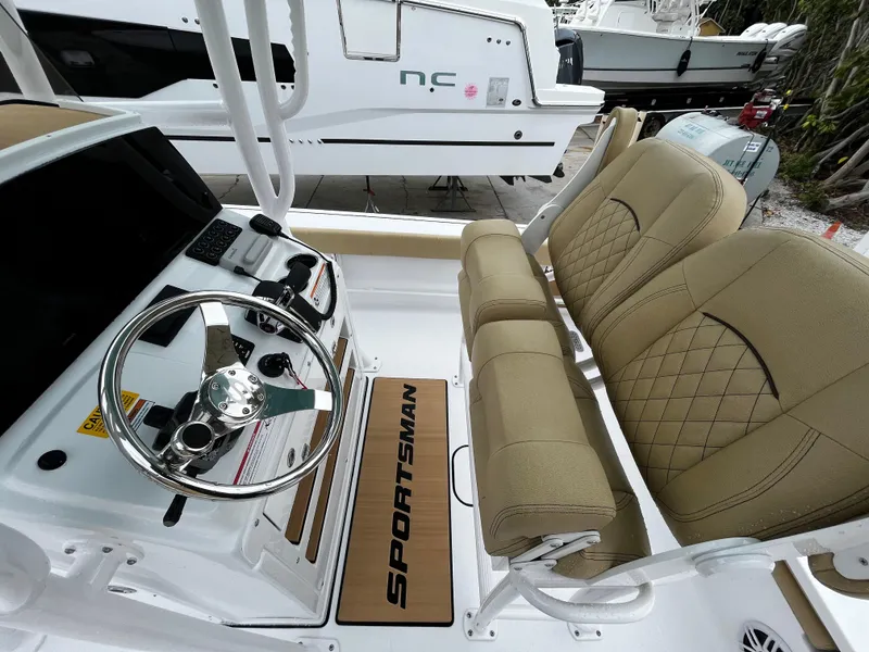 Slide: The Image of 2024 Sportsman Masters 227 Bay Boat interior with steering wheel and beige seating. - 15