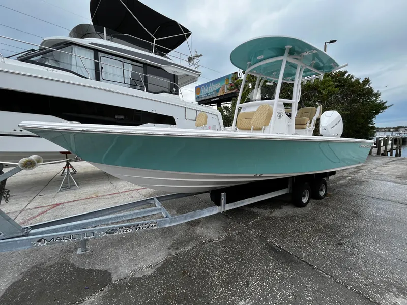 Slide: The Image of 2024 Sportsman Masters 227 Bay Boat on trailer, docked beside a larger yacht. - 2