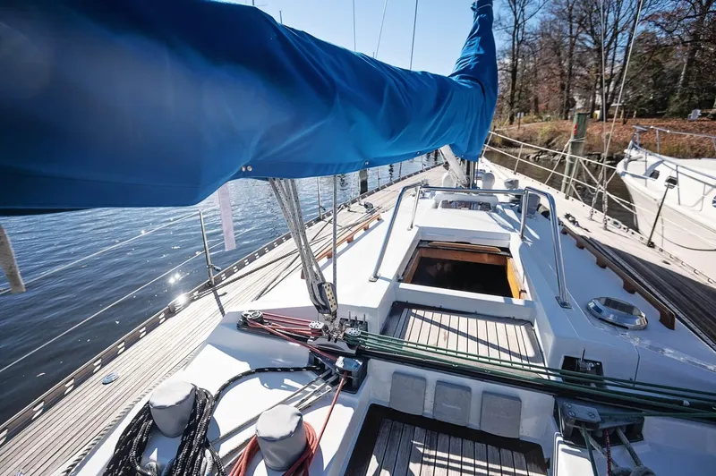 Slide: The Image of 1977 Baltic 42 sailboat deck with blue sail cover, docked by calm water. - 20