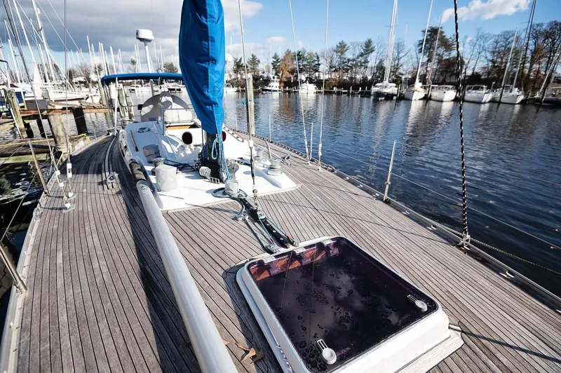 Slide: The Image of Sailboat Baltic 42, 1977 model, docked at marina with wooden deck and blue sail cover. - 22