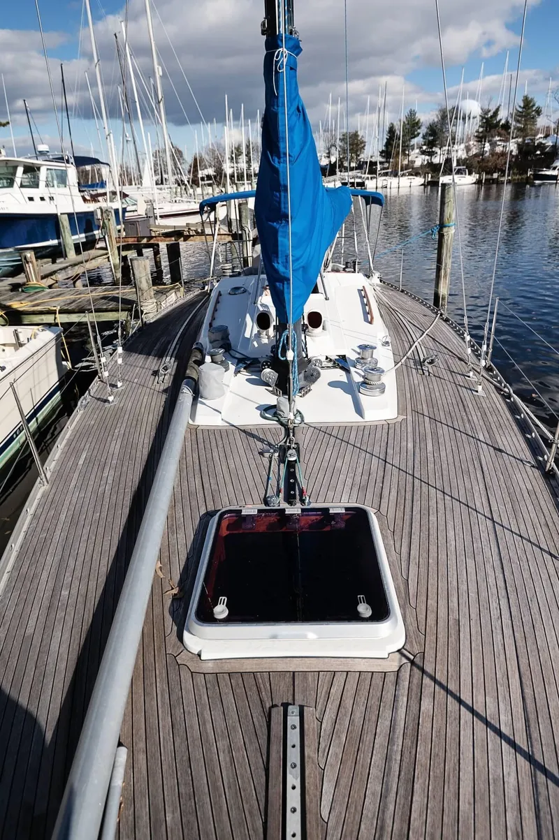 Slide: The Image of 1977 Baltic 42 sailboat docked, featuring wooden deck and blue sail cover. - 23