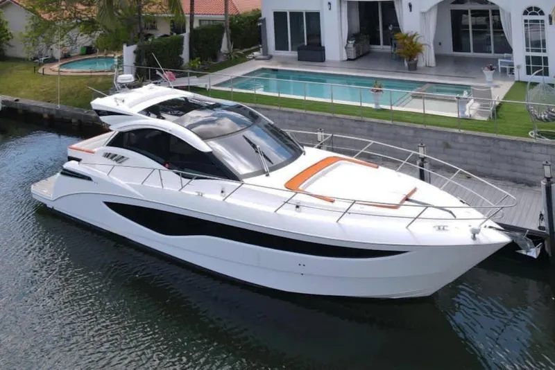 Slide: The Image of 2017 Galeon 445 HTS yacht docked near a modern waterfront home. - 0