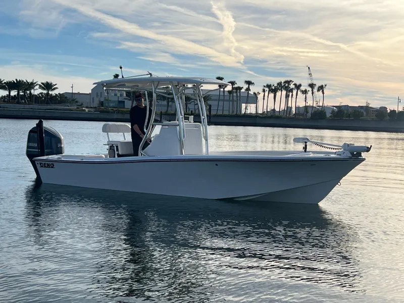 Slide: The Image of 2024 Deno 2400 CC boat on calm water with palm trees in the background. - 1