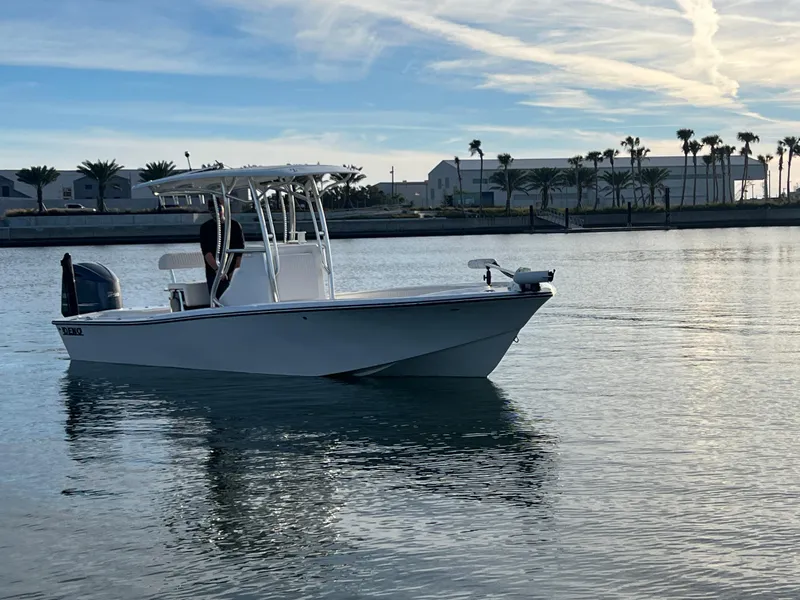 Slide: The Image of 2024 Deno 2400 CC boat cruising on calm waters near a coastal marina. - 13
