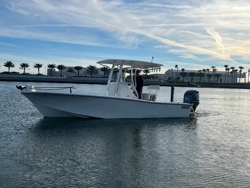 Slide: The Image of 2024 Deno 2400 CC boat cruising on calm water with a scenic background. - 14