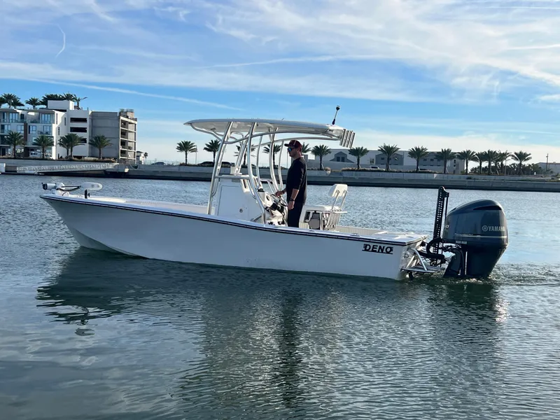 Slide: The Image of 2024 Deno 2400 CC boat cruising on calm water near modern buildings. - 16