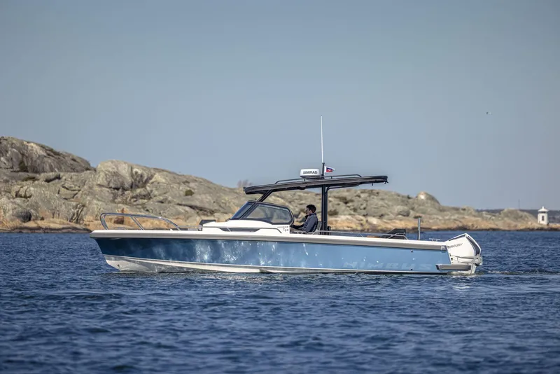 The Image of 2024 Nimbus T9 boat cruising on a calm sea near rocky shore. - 0