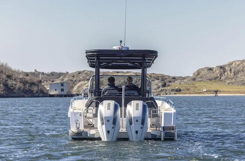Slide: The Image of 2024 Nimbus T9 boat cruising on a scenic lake with rocky shoreline. - 6