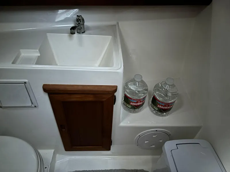 Slide: The Image of 1992 Bayliner 3288 Motoryacht bathroom with sink, cabinet, and water bottles. - 23