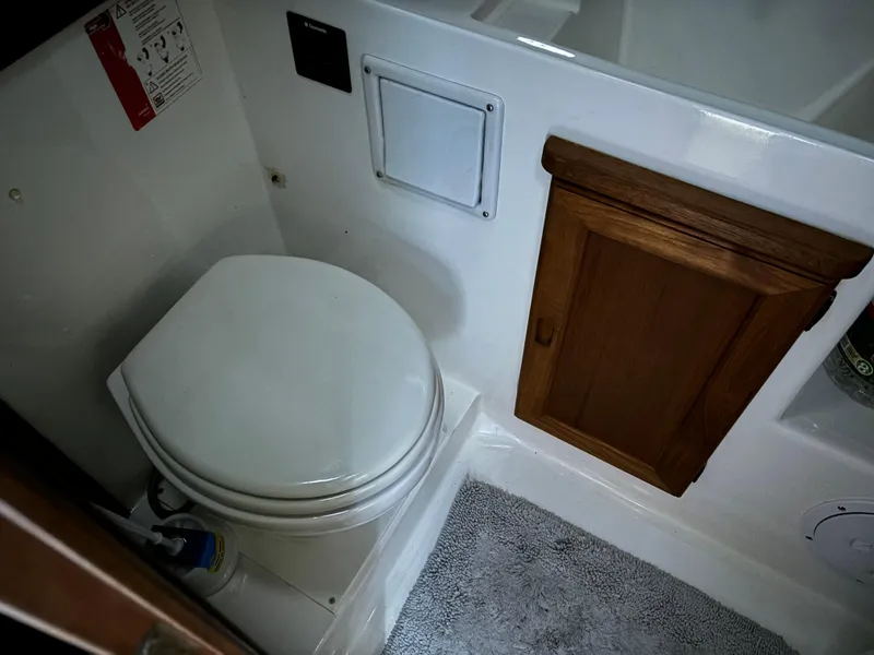 Slide: The Image of 1992 Bayliner 3288 Motoryacht bathroom with toilet, wooden cabinet, and gray rug. - 29