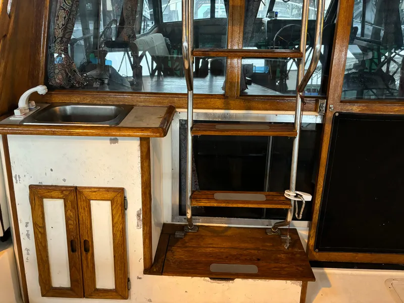 Slide: The Image of 1992 Bayliner 3288 Motoryacht interior with sink, wooden cabinets, and ladder. - 3
