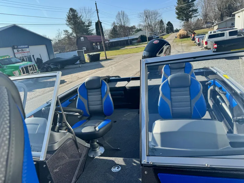Slide: The Image of 2024 Ranger 1880MS boat with blue and gray seats, parked outdoors. - 9