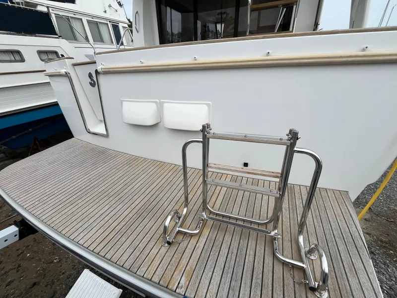 Slide: The Image of 2013 Beneteau Swift Trawler 34 with stainless steel ladder on wooden deck. - 11