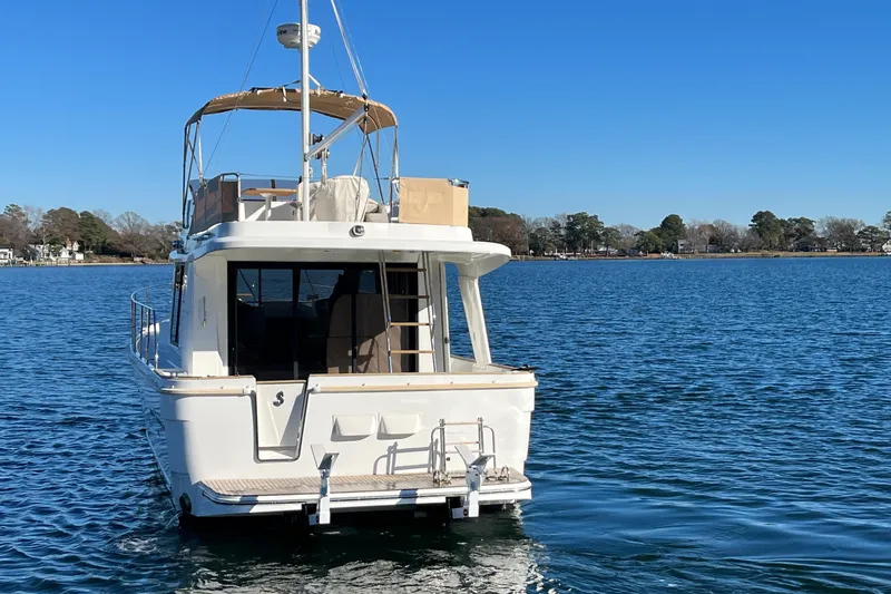 Slide: The Image of 2013 Beneteau Swift Trawler 34 on calm water, rear view, clear blue sky. - 2