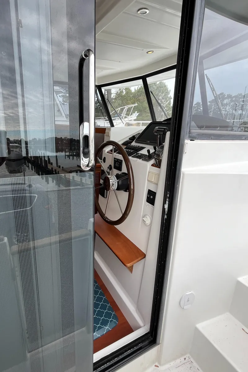 Slide: The Image of 2013 Beneteau Swift Trawler 34 helm station with wooden steering wheel and glass door. - 22